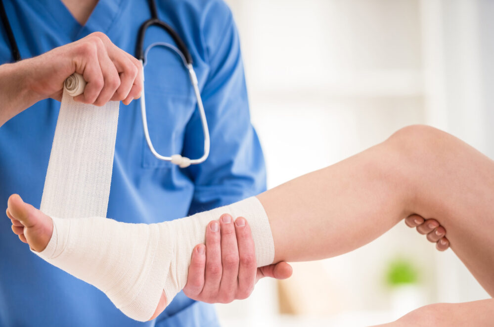 Podiatrist treating an ankle sprain by wrapping the ankle