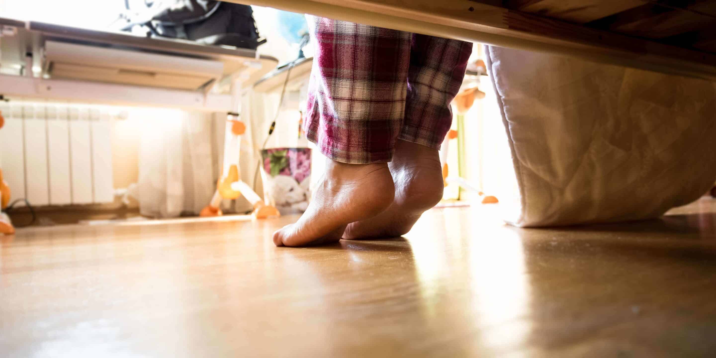 Photo from under the bed on barefoot woman in pajamas