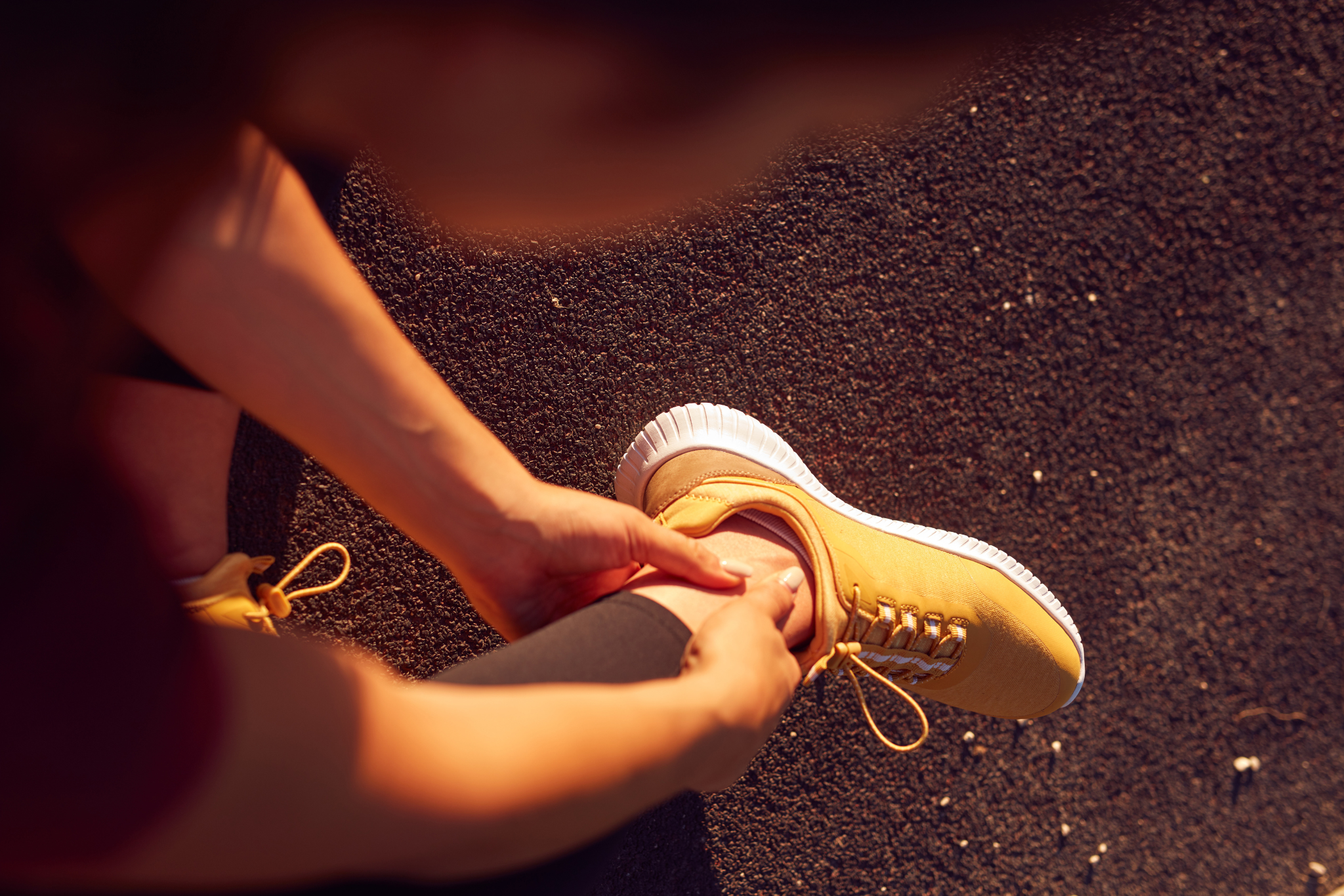 Young woman with ankle and leg pain during jogging and exercise in urban park.