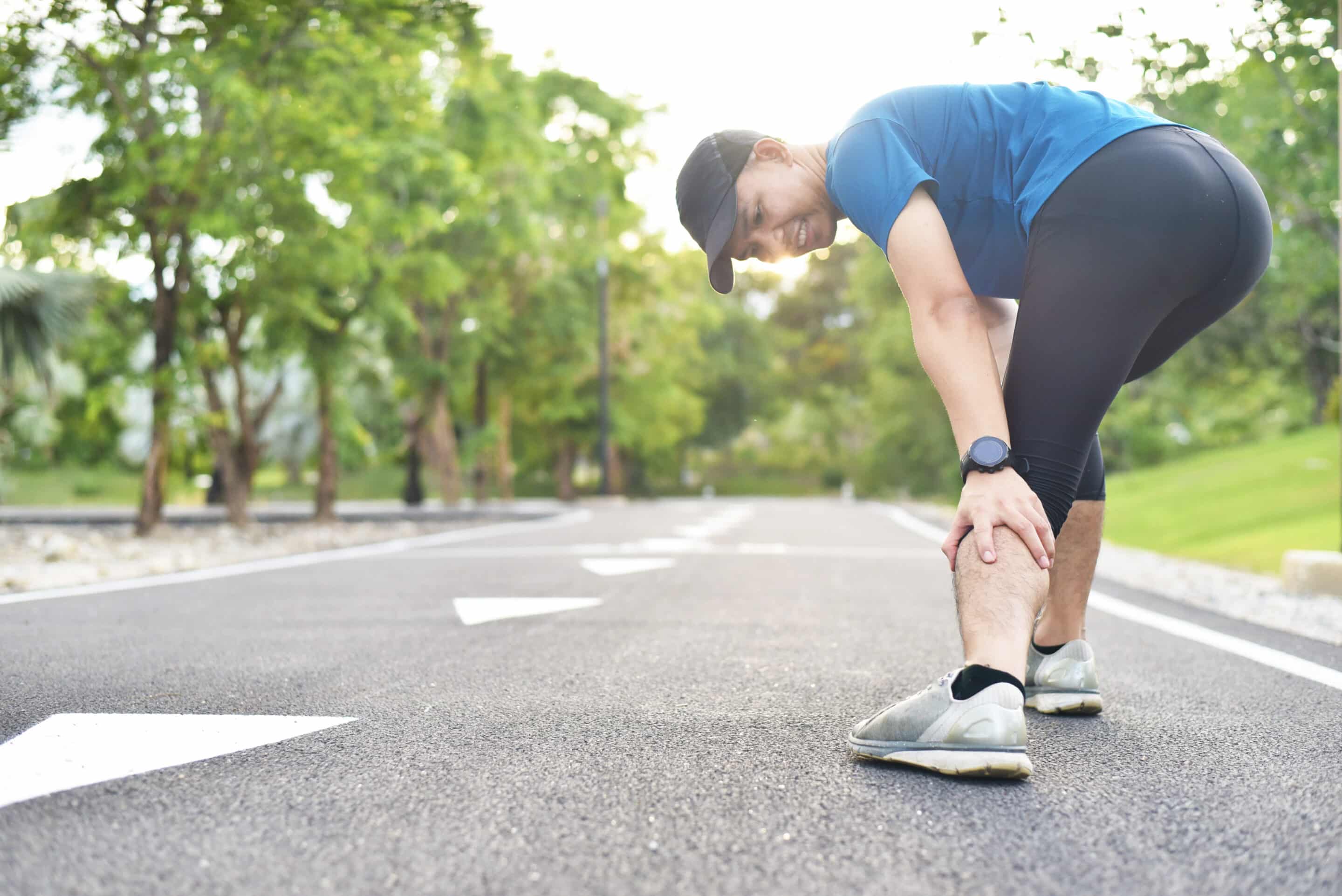 close up of young Asian sports man has pain at muscles and joints during outdoor exercise, over trainning or running and sport injuty concept